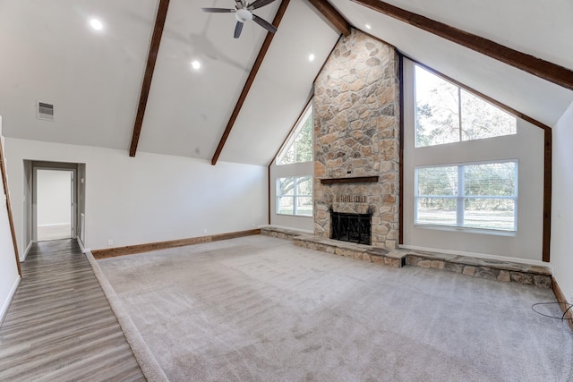 unfurnished living room with carpet, a fireplace, ceiling fan, high vaulted ceiling, and beam ceiling