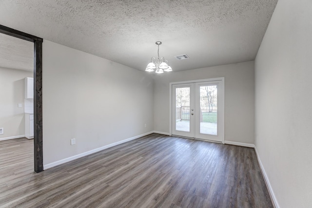 unfurnished room with a textured ceiling, an inviting chandelier, wood-type flooring, and french doors