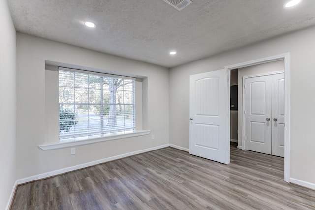 unfurnished bedroom with a textured ceiling and light hardwood / wood-style flooring