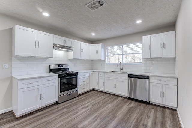 kitchen featuring white cabinetry, stainless steel appliances, decorative backsplash, sink, and light hardwood / wood-style flooring