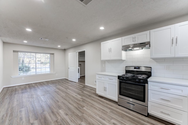 kitchen featuring tasteful backsplash, white cabinets, light wood-type flooring, and stainless steel gas stove