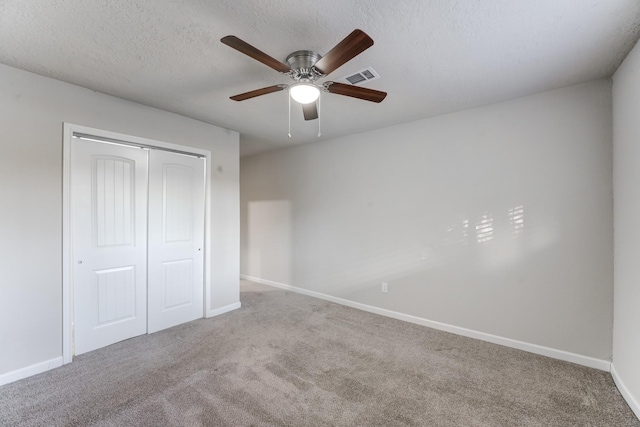 unfurnished bedroom with ceiling fan, a closet, a textured ceiling, and carpet flooring