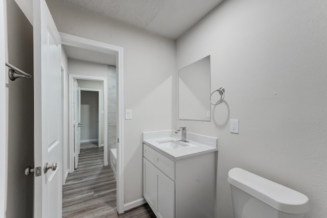 bathroom featuring hardwood / wood-style flooring, a textured ceiling, toilet, and vanity