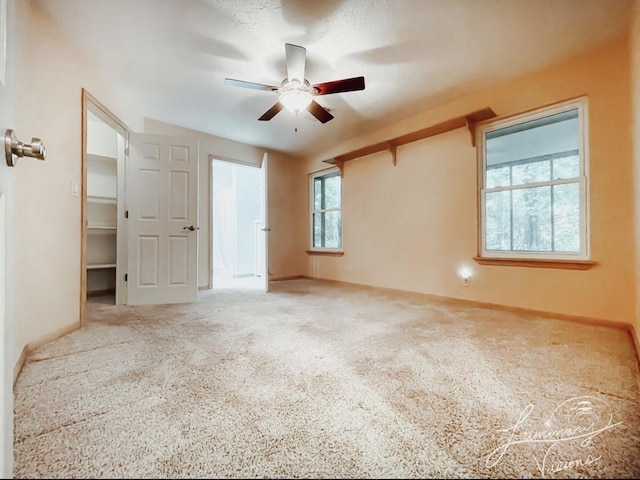 unfurnished bedroom with ceiling fan, a walk in closet, a closet, and carpet floors