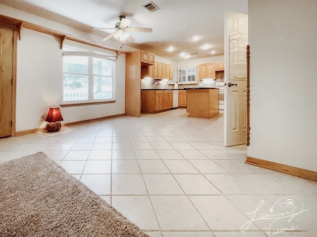 kitchen featuring light tile patterned floors, ceiling fan, light brown cabinets, white dishwasher, and range