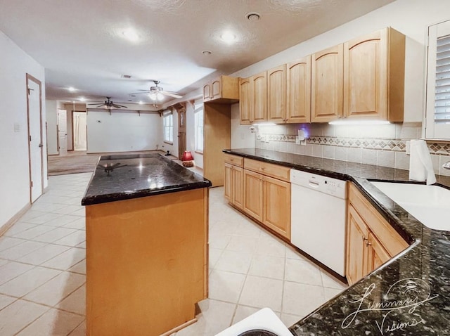 kitchen featuring light tile patterned flooring, light brown cabinetry, white dishwasher, dark stone countertops, and sink