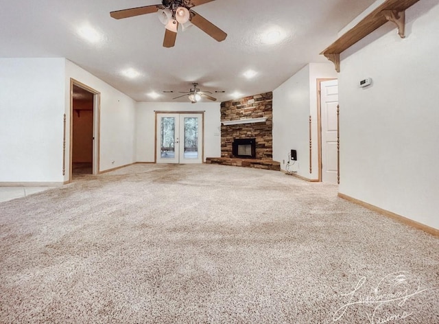 unfurnished living room with ceiling fan, carpet flooring, a fireplace, and french doors