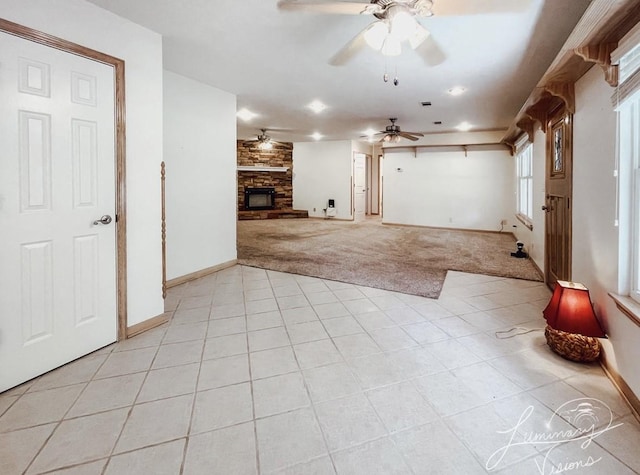 unfurnished living room with ceiling fan, light colored carpet, and a fireplace