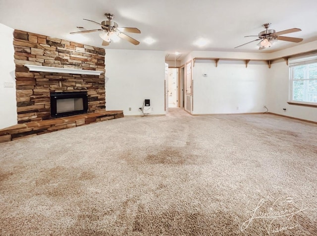 unfurnished living room featuring ceiling fan, carpet floors, and a stone fireplace