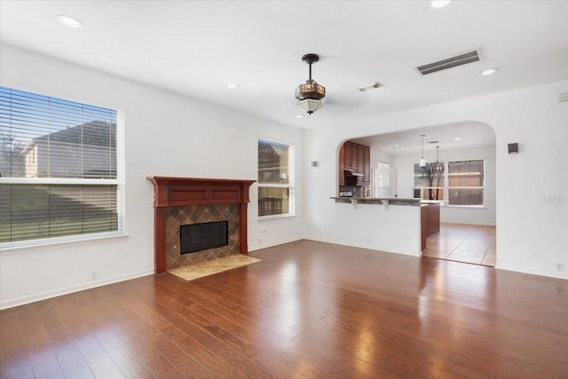 unfurnished living room with plenty of natural light, dark hardwood / wood-style floors, and a fireplace