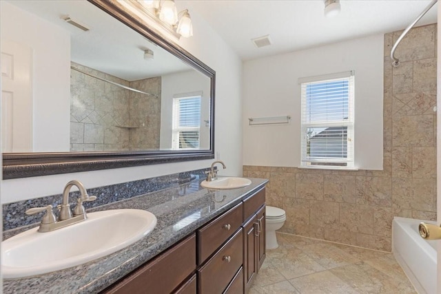 full bathroom featuring toilet, a healthy amount of sunlight, tile walls, and vanity