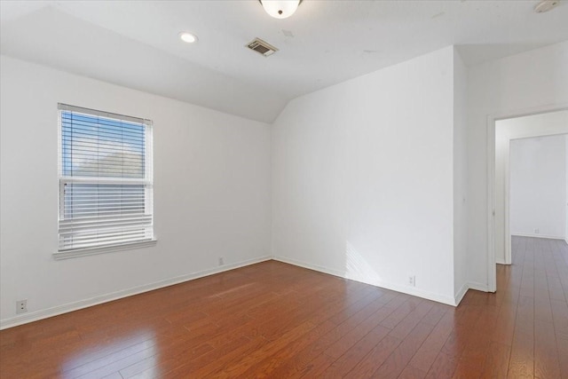 empty room featuring vaulted ceiling and dark hardwood / wood-style floors