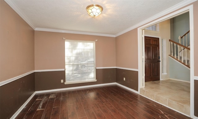 spare room featuring dark wood-type flooring, ornamental molding, and a textured ceiling