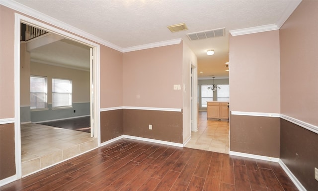 spare room featuring an inviting chandelier, crown molding, and a textured ceiling