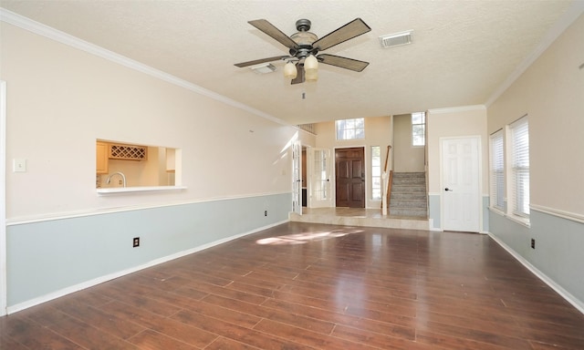 unfurnished living room with dark wood-type flooring, a textured ceiling, sink, and ornamental molding