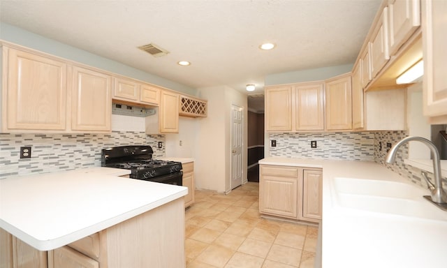 kitchen featuring kitchen peninsula, black gas range oven, tasteful backsplash, light brown cabinetry, and sink