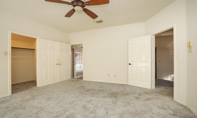 unfurnished bedroom with a spacious closet, light colored carpet, and ceiling fan