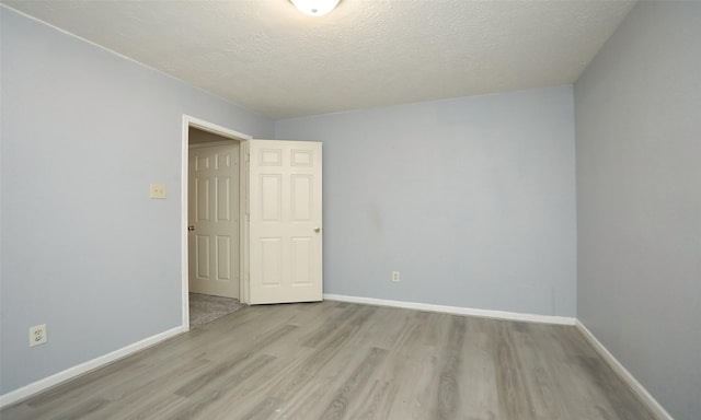 unfurnished room with light hardwood / wood-style floors and a textured ceiling