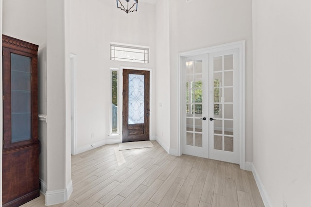 entrance foyer with light wood-type flooring, a high ceiling, and french doors