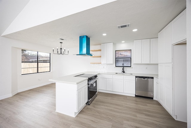 kitchen with island exhaust hood, stainless steel appliances, white cabinets, and sink