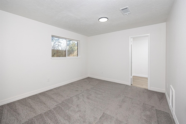 carpeted spare room with a textured ceiling