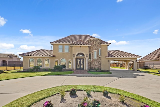 mediterranean / spanish-style house featuring a front lawn, a carport, and french doors