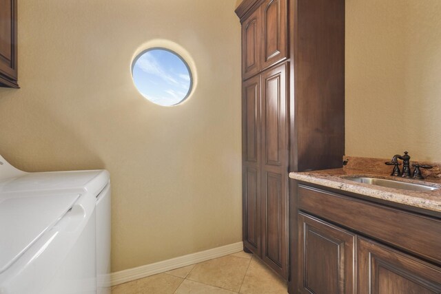 laundry area featuring sink, light tile patterned floors, cabinets, and independent washer and dryer