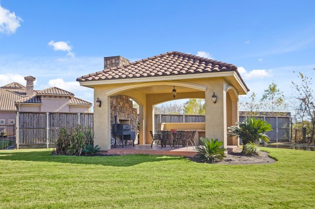 rear view of house featuring a patio area, a gazebo, a lawn, and a fireplace