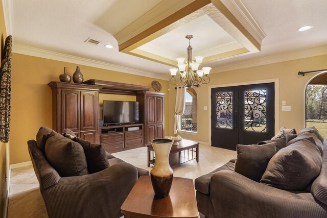 tiled living room with a tray ceiling, ornamental molding, french doors, and an inviting chandelier