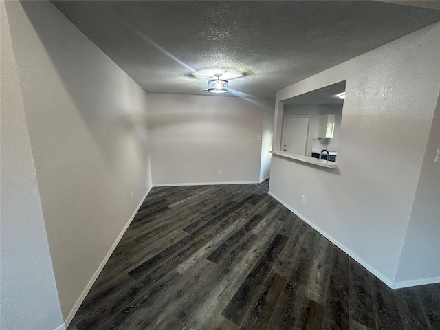 unfurnished room with a textured ceiling and dark hardwood / wood-style flooring