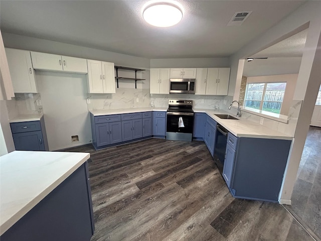 kitchen with white cabinets, appliances with stainless steel finishes, tasteful backsplash, blue cabinetry, and sink