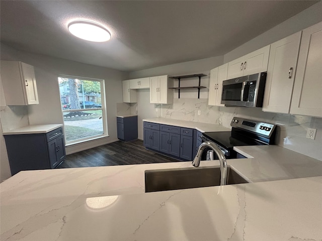 kitchen featuring white cabinets, stainless steel appliances, blue cabinetry, and sink