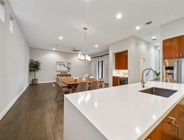 kitchen featuring ceiling fan, a large island with sink, sink, hanging light fixtures, and dark hardwood / wood-style flooring