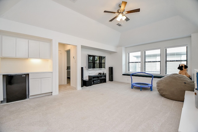 carpeted living room with ceiling fan and vaulted ceiling