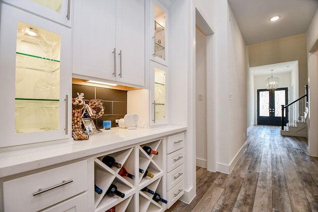 bar with white cabinets, french doors, an inviting chandelier, backsplash, and dark hardwood / wood-style floors