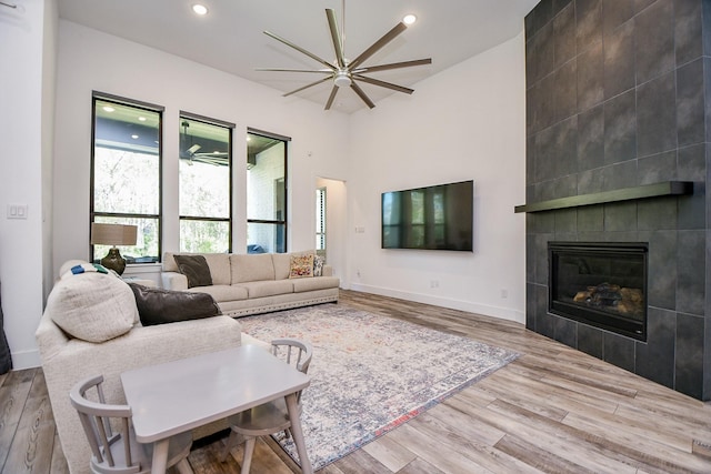 living room featuring ceiling fan, light hardwood / wood-style floors, and a fireplace