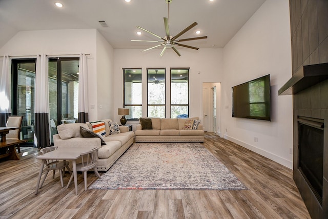 living room with ceiling fan, light hardwood / wood-style flooring, and a tile fireplace