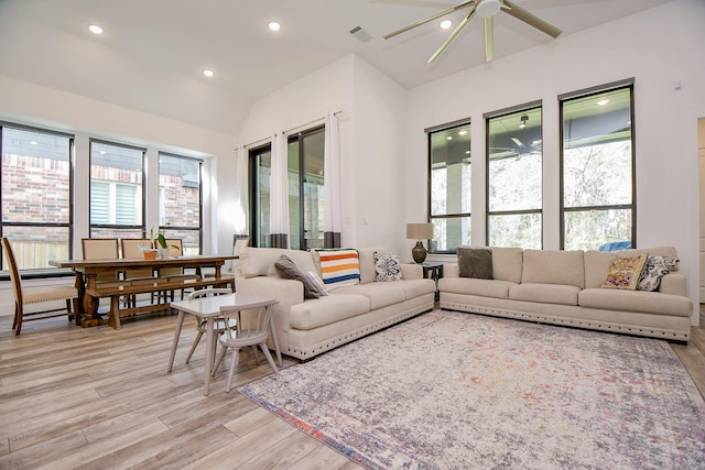 living room featuring light wood-type flooring, ceiling fan, a healthy amount of sunlight, and lofted ceiling