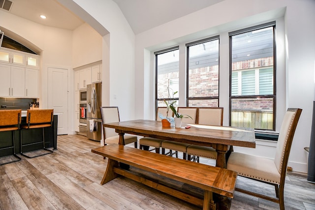 dining space with light hardwood / wood-style floors and lofted ceiling