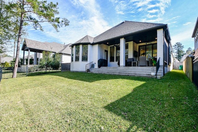 rear view of house with ceiling fan and a yard