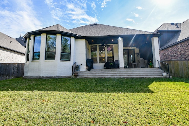 rear view of property with ceiling fan, a yard, and a patio