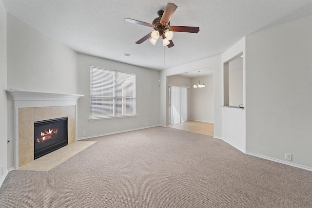 unfurnished living room with ceiling fan with notable chandelier, a textured ceiling, light carpet, and a fireplace