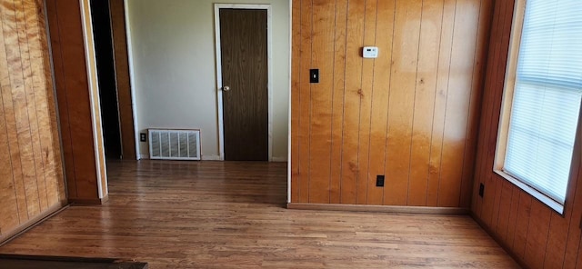 unfurnished room featuring wood walls, wood finished floors, and visible vents