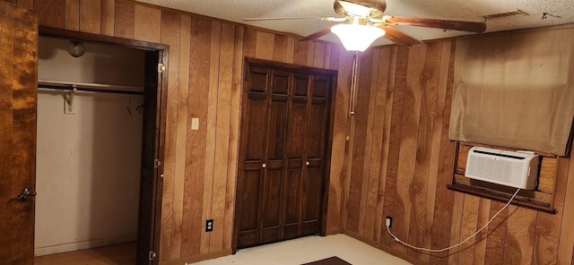 interior space featuring two closets, visible vents, ceiling fan, wooden walls, and cooling unit