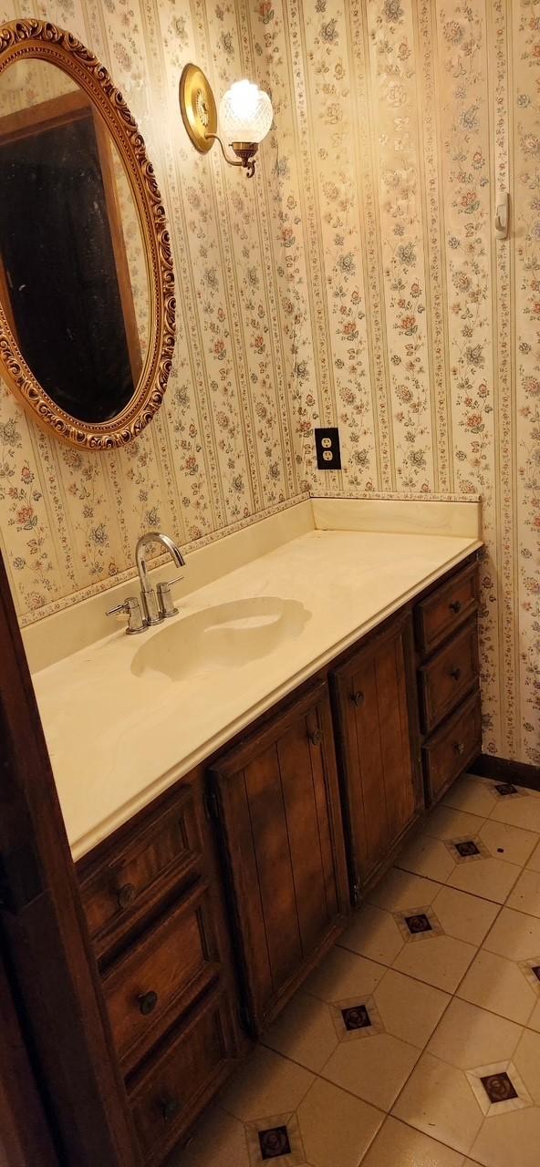 bathroom with tile patterned flooring, vanity, and wallpapered walls