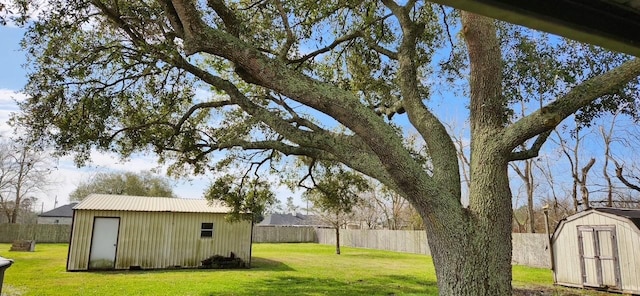 view of yard featuring an outbuilding, a storage unit, and fence