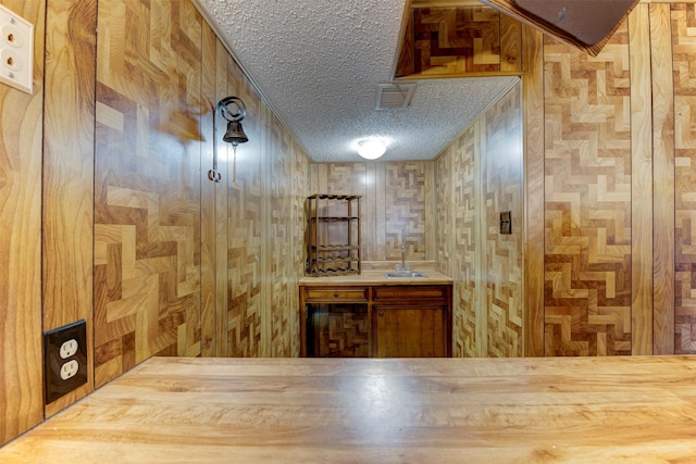 wine cellar with visible vents, a sink, and a textured ceiling