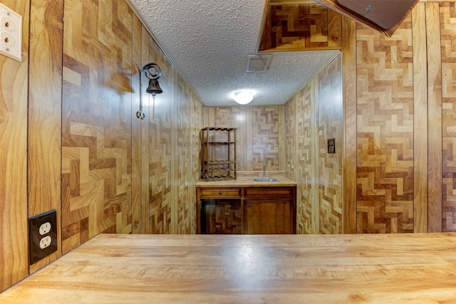 2180 Washington Ave, Alvin, TX 77511 - interior space featuring visible vents, wooden walls, a textured ceiling, and a sink