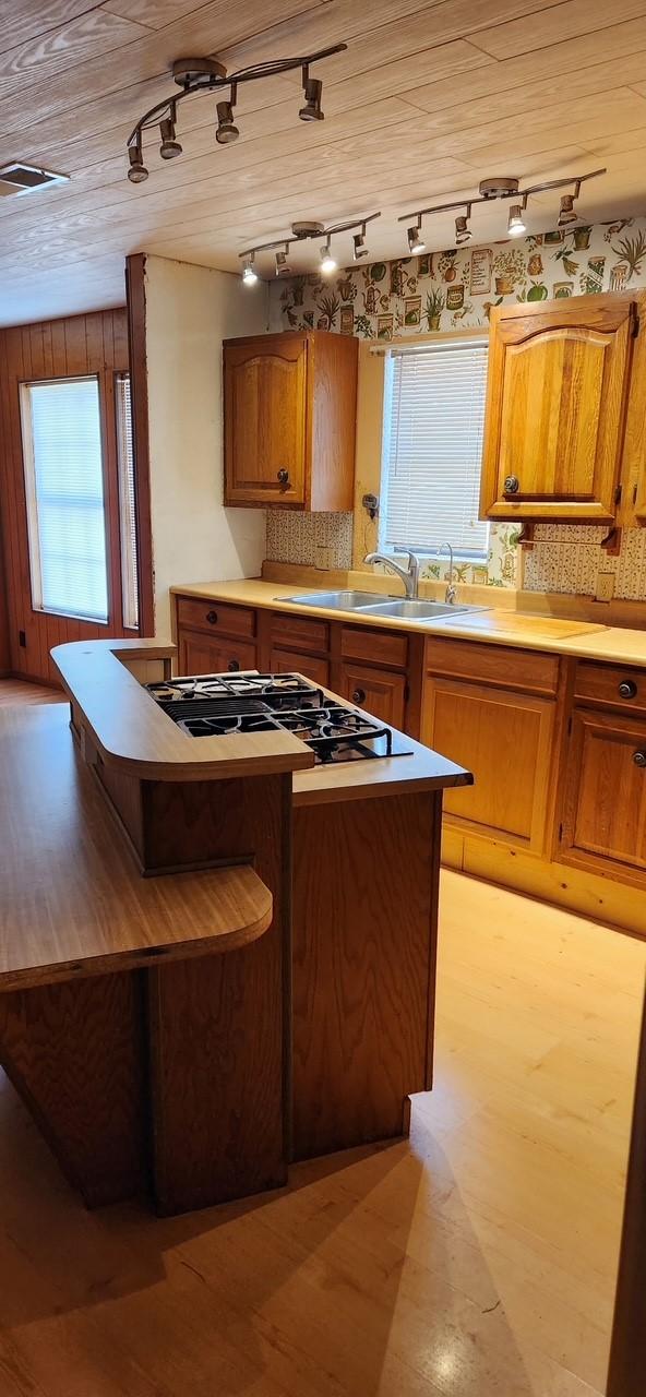 kitchen with a center island, tasteful backsplash, light countertops, brown cabinetry, and a sink