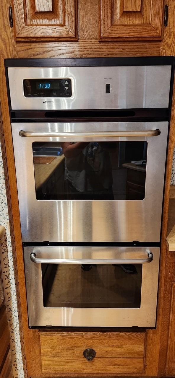 room details featuring stainless steel double oven and brown cabinets